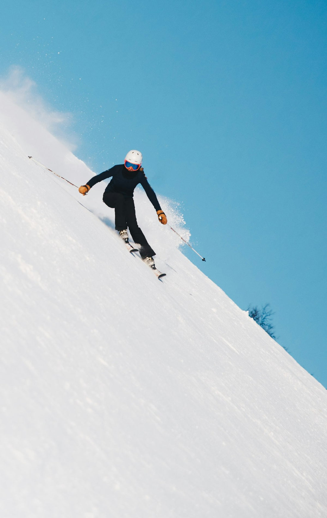 Alpine skier carving down snow-covered mountain slope in bright sunlight