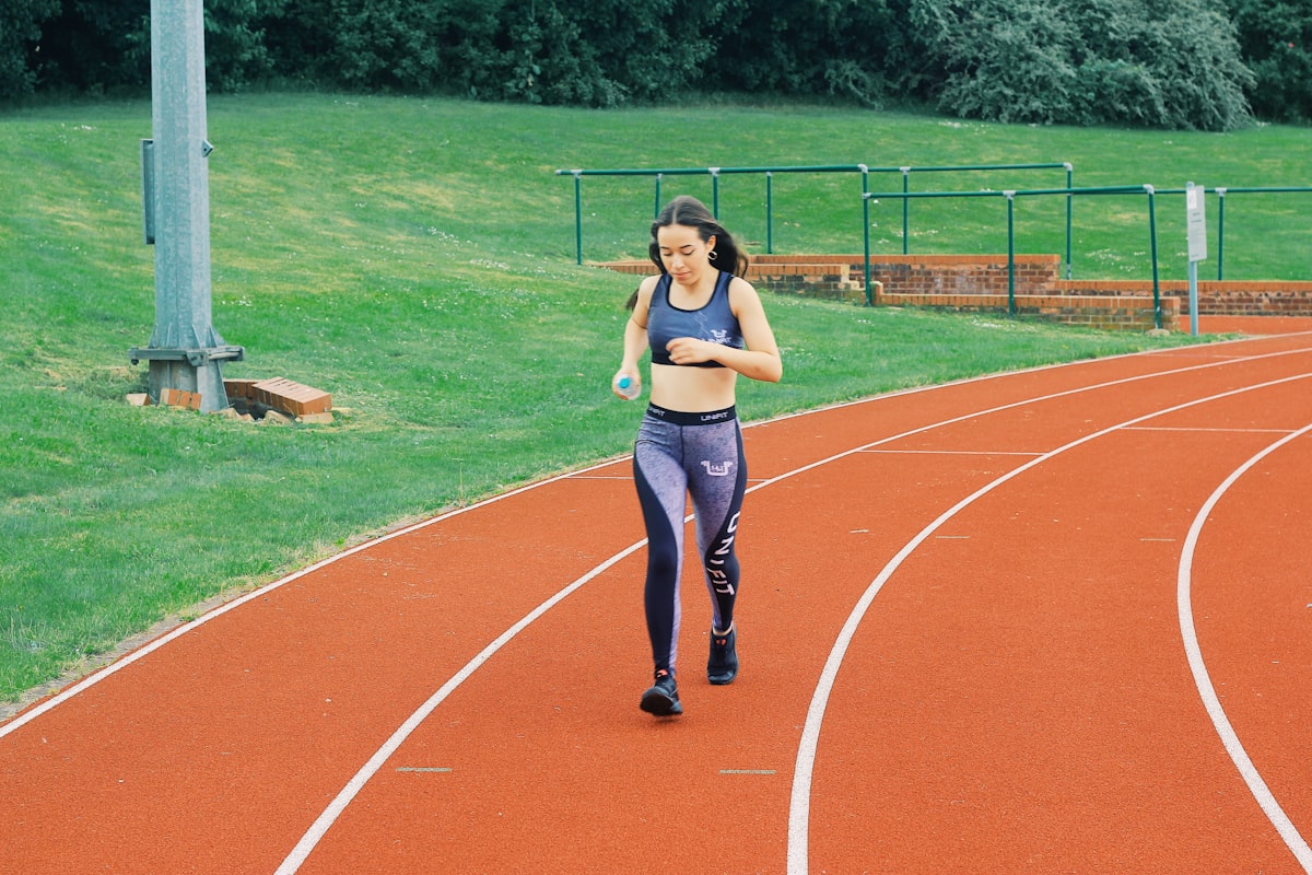 Female athlete walking on red running track at sports training facility